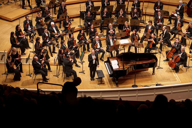 the audience looks down from the balcony as pianist Simon Trpčeski takes an encore bow