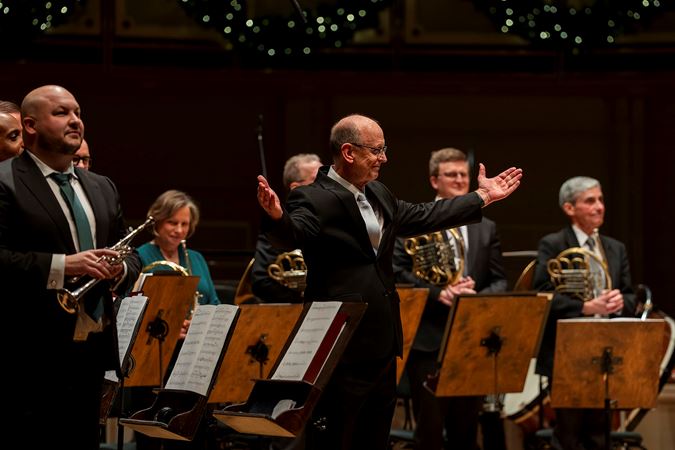 conductor Michael Mulcahy gestures for the ensemble to take a bow