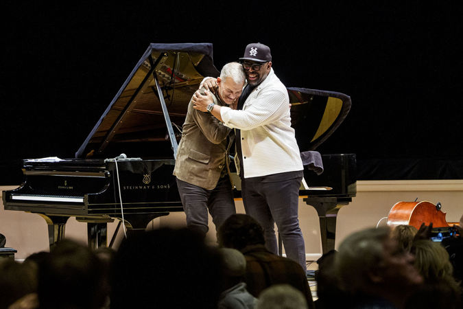 Brad Mehldau and Christian McBride hug in front of the piano after their duo performance