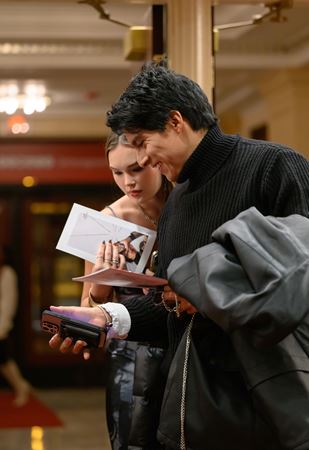 two young audience members pull up their tickets on a phone as they enter Orchestra Hall