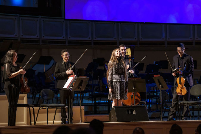 Young Composers Initiative participant Sylvia Pine bowing on stage