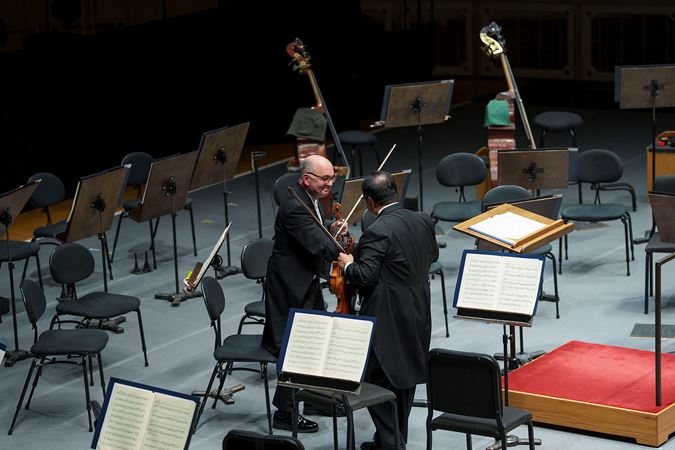 Violin players Robert Chen and Baird Dodge shake hands on stage during the last movement of Haydn's Farewell Symphony