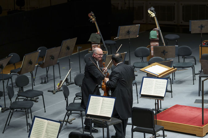 Violin players Robert Chen and Baird Dodge shake hands on stage during the last movement of Haydn's Farewell Symphony