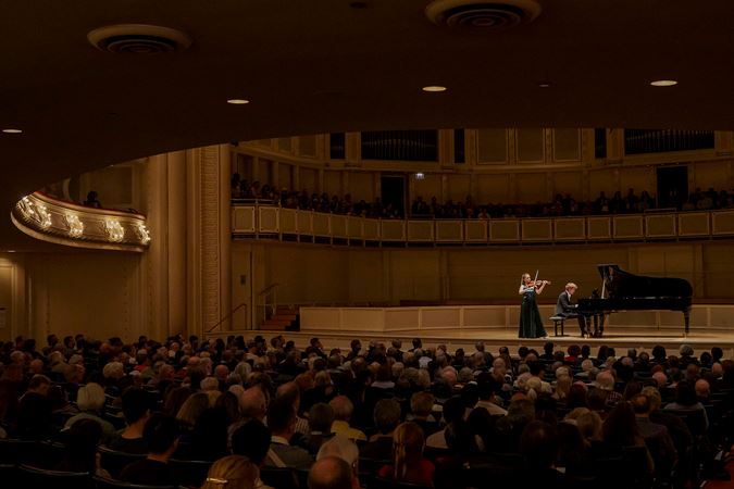Wide shot of violinist Julia Fischer and pianist Jan Lisiecki performing on stage