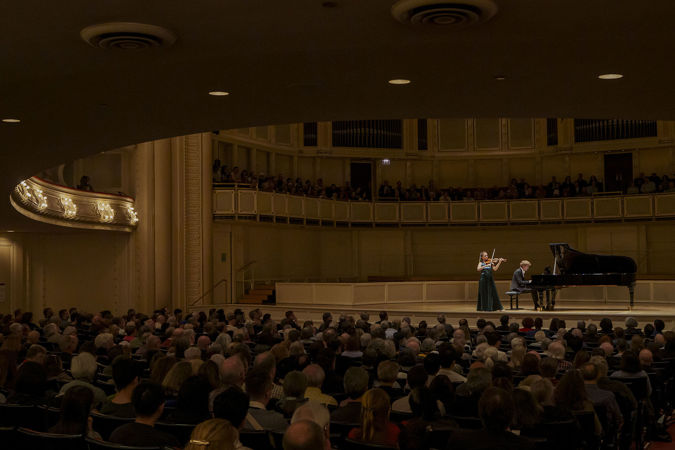 Wide shot of violinist Julia Fischer and pianist Jan Lisiecki performing on stage