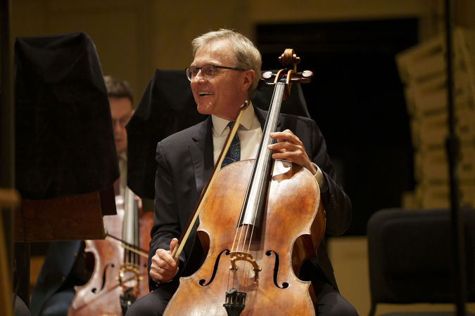 Close up shot of CSO principal cello John Sharp smiling as he looks at the music he's about to perform on stage