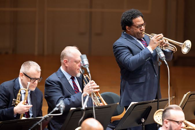 A Jazz at Lincoln Center Orchestra trumpet player standing up while playing a solo.