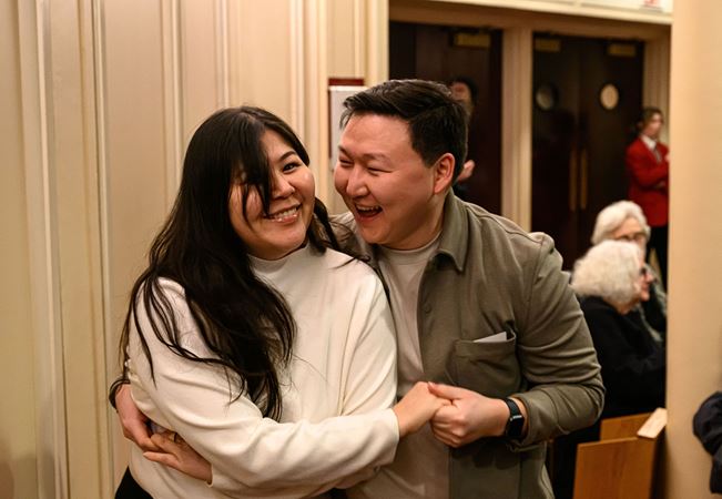 a couple in the audience smiles and holds hands
