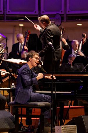 Closeup action shot of singer-songwriter Ben Folds singing on stage at the piano with the CSO