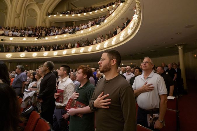 The audience listens intently as the orchestra performs The Star Spangled Banner to open the concert