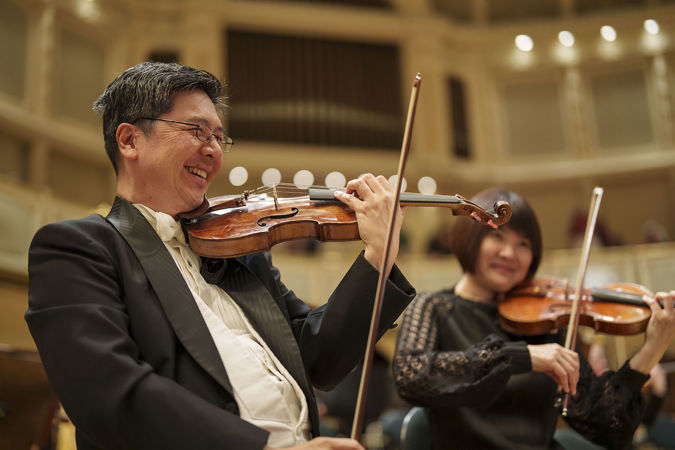 CSO violin Cornelius Chiu smiles wide for the camera during warm-ups