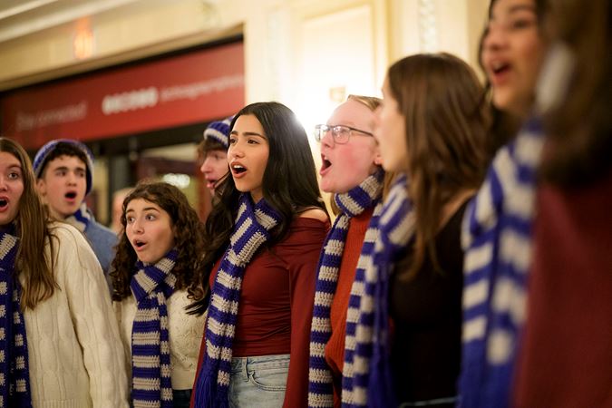 Group shot of a school choir ensemble singing in the Main Floor lobby before the concert