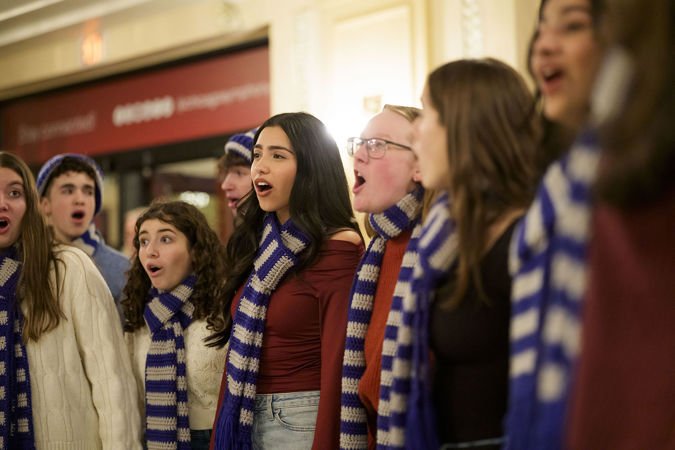 Group shot of a school choir ensemble singing in the Main Floor lobby before the concert