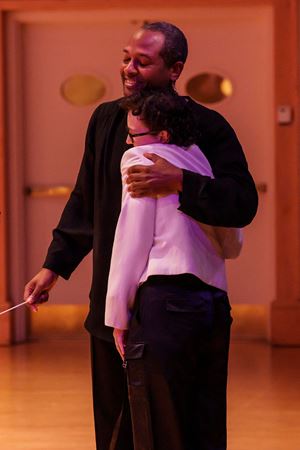 young composer hugging conductor