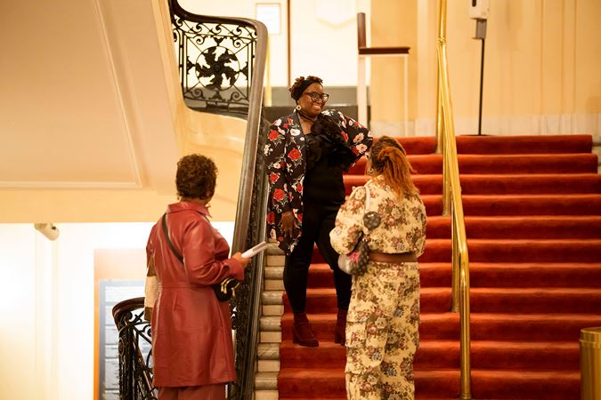 A patron smiling on the second floor red-carpeted stairwell in Orchestra Hall