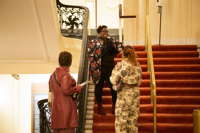 A patron smiling on the second floor red-carpeted stairwell in Orchestra Hall