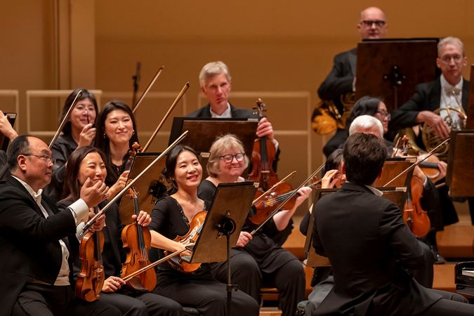 orchestra members applaud Shani