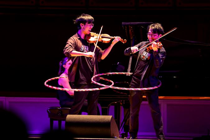 Eddy and Brett of TwoSet Violin perform while hula hooping