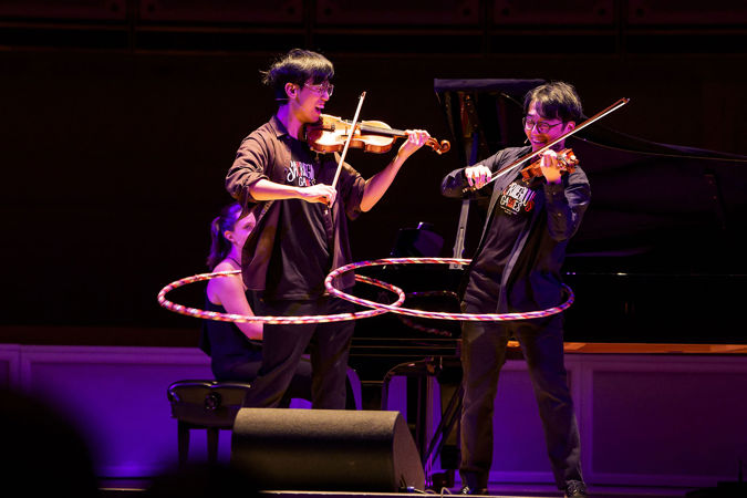 Eddy and Brett of TwoSet Violin perform while hula hooping