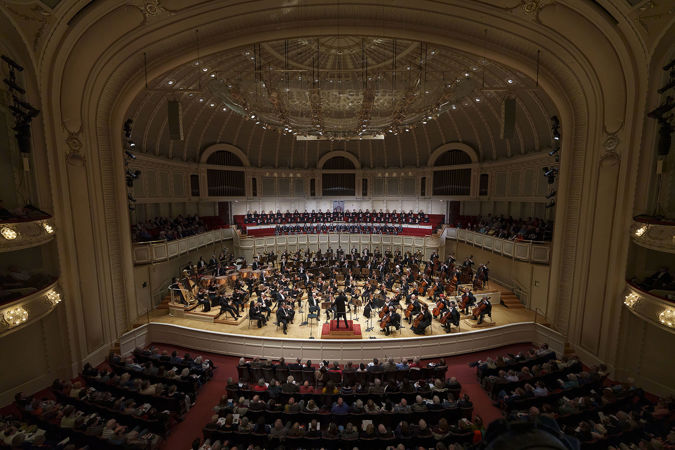 A wide shot of Zell Music Director Designate Klaus Mäkelä leading the Chicago Symphony Orchestra and Chorus and Uniting Voices Chicago
