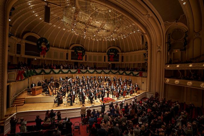 the full orchestra stands to bow after the performance