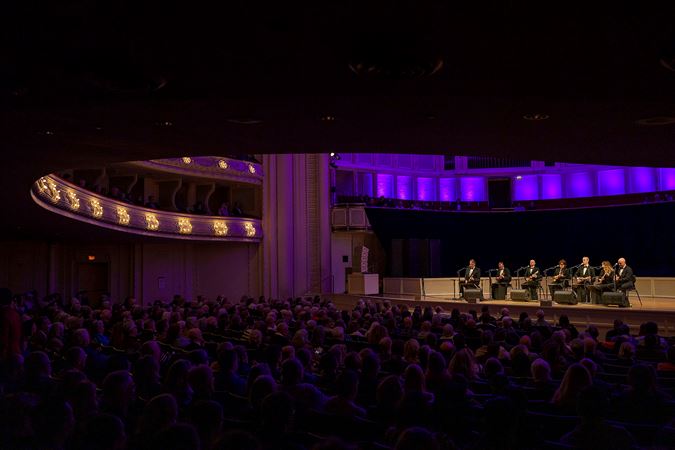 point of view from the back right side of the main floor as the audience watches, enraptured