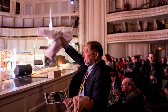 a man in the front row waves enthusiastically as the performers take a bow