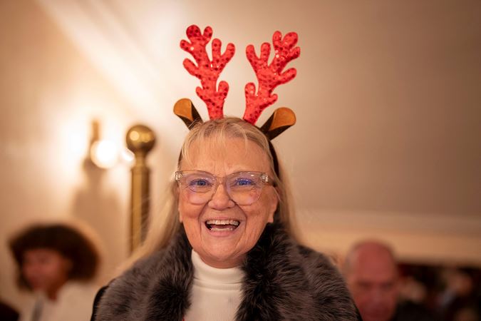 A closeup of a smiling patron wearing a reindeer antler headband