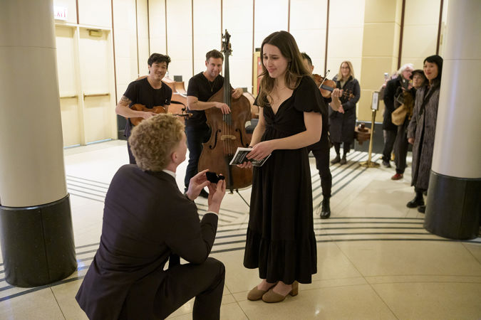 Couple Cade and Isabella are caught tearing up mid-proposal, as Time For Three serenades them in the Symphony Center Rotunda