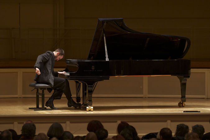 Alexandre Kantorow playing the piano on stage at his recital