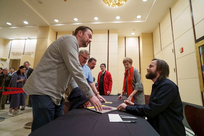 pianist Daniil Trifonov smiles at a fan as he signs their vinyl record in the Rotunda after the concert