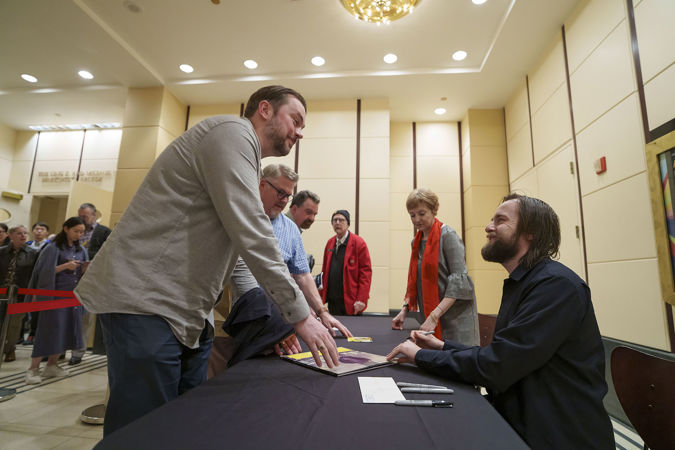 pianist Daniil Trifonov smiles at a fan as he signs their vinyl record in the Rotunda after the concert