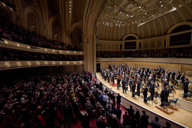 Wide shot of Krill Petrenko and Berliner Philharmoniker bowing on stage