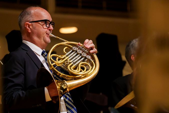 Close up action shot of CSO horn David Griffin warming up before the concert on stage