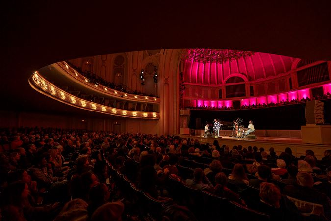 a wide shot of the audience watching Cécile perform