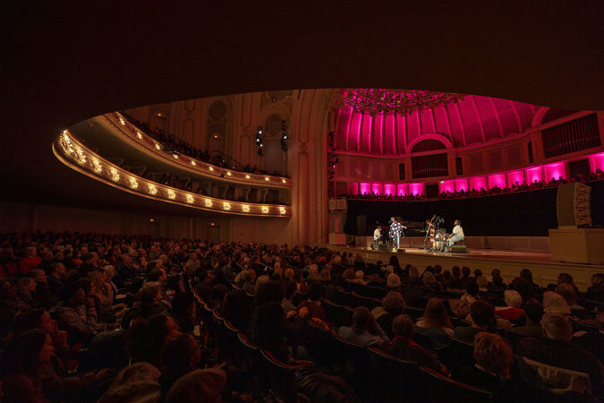 a wide shot of the audience watching Cécile perform