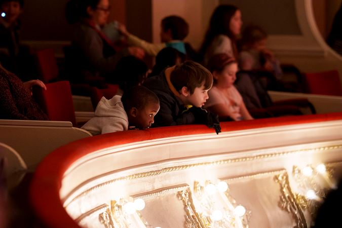 Close up of two young patrons watching the performance from the box level