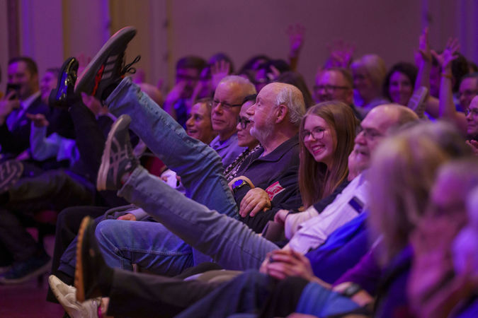 audience members laugh and kick their legs in the air during a comedic audience participation moment