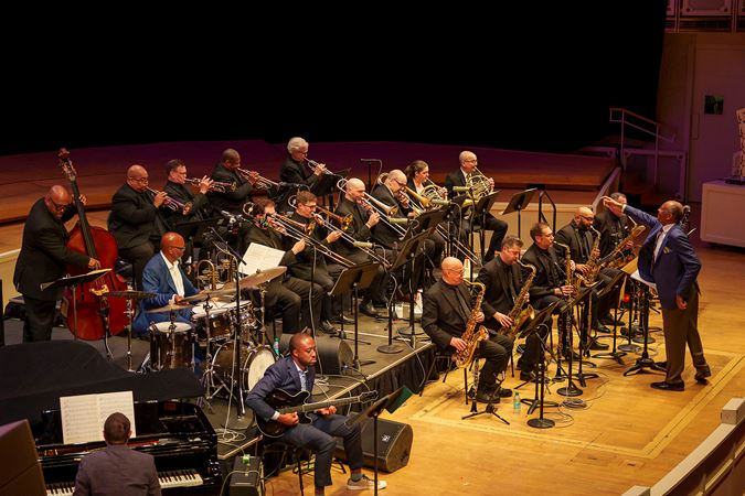 John Clayton extends an arm towards the trombone section while directing the Chicago Jazz Orchestra in Oscar Peterson's Africa Suite