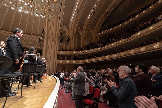 full orchestra bowing while the audience cheers