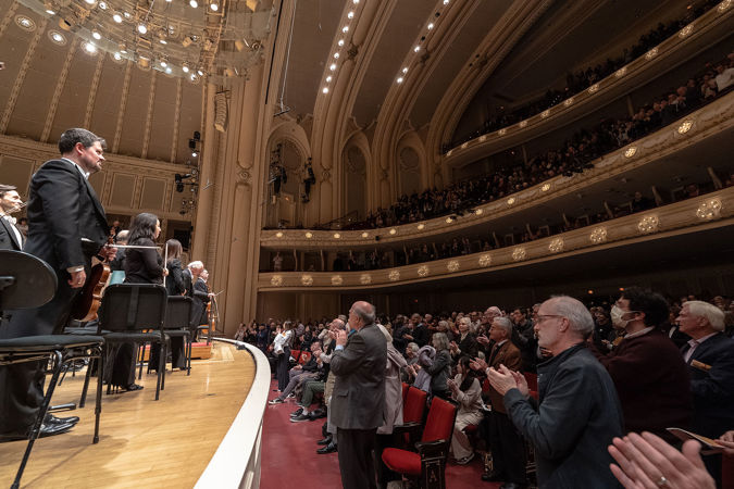 full orchestra bowing while the audience cheers