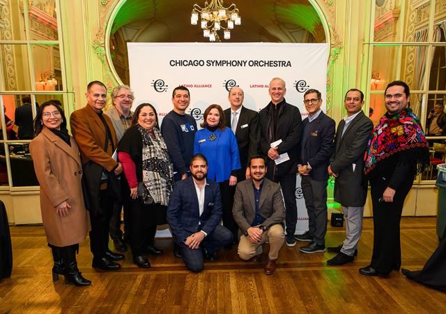 members of the CSO Latino Alliance pose by a photo wall with special guests Pacho Flores and Carlos Miguel Prieto