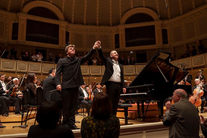 conductor Jakub Hrůša and pianist Simon Trpčeski raise their conjoined hands in a bow