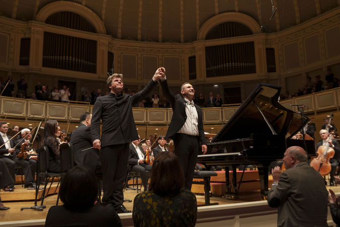 conductor Jakub Hrůša and pianist Simon Trpčeski raise their conjoined hands in a bow
