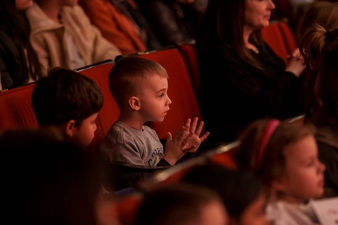 A young boy claps in his seat on the main floor