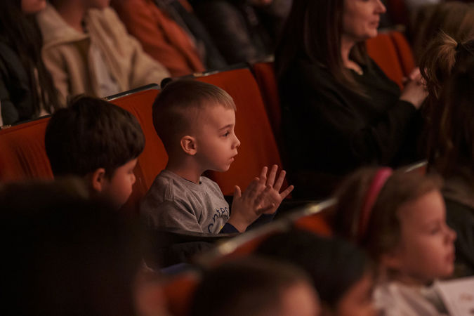 A young boy claps in his seat on the main floor