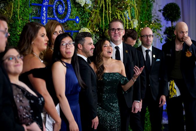 Group shot of CSO Overture Council members smiling behind the step-and-repeat plant and butterfly backdrop