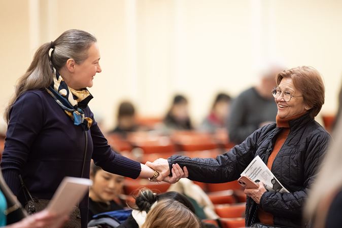 two audience members on the main floor greet each other as they find their seats for the show