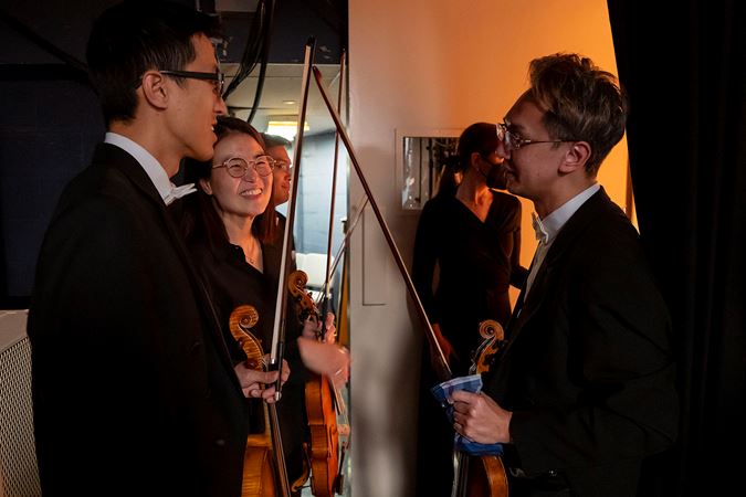 Three CSO musicians smiling and talking by backstage door