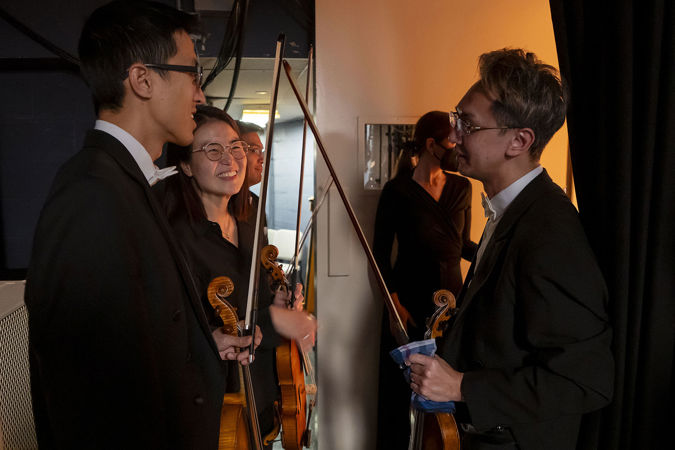 Three CSO musicians smiling and talking by backstage door
